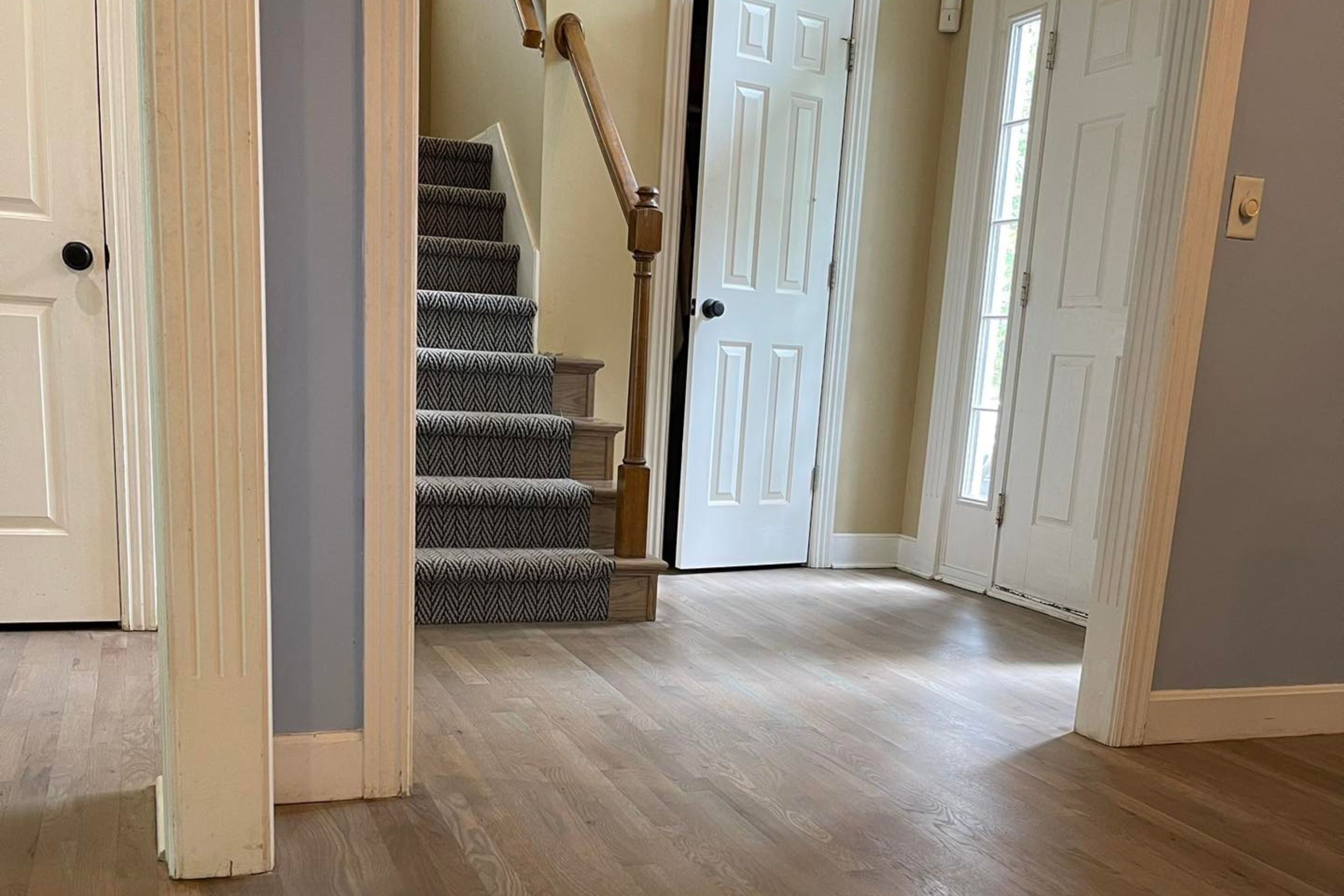Newly installed hardwood flooring and staircase in a Kansas City, KS home entryway.