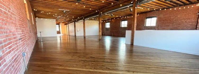 Hardwood floor refinishing in progress inside Leawood, KS industrial loft with brick walls and exposed beams