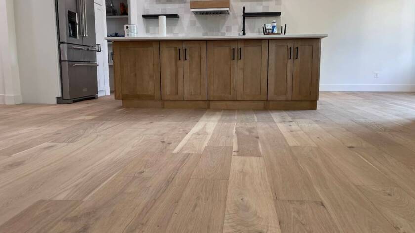 Wood floor repair in Kansas City KS kitchen area featuring light-toned hardwood planks and an island