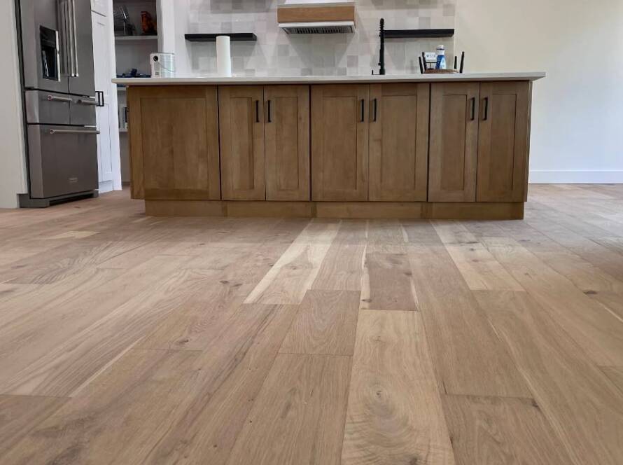 Wood floor repair in Kansas City KS kitchen area featuring light-toned hardwood planks and an island