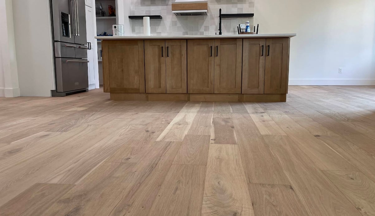 Wood floor repair in Kansas City KS kitchen area featuring light-toned hardwood planks and an island